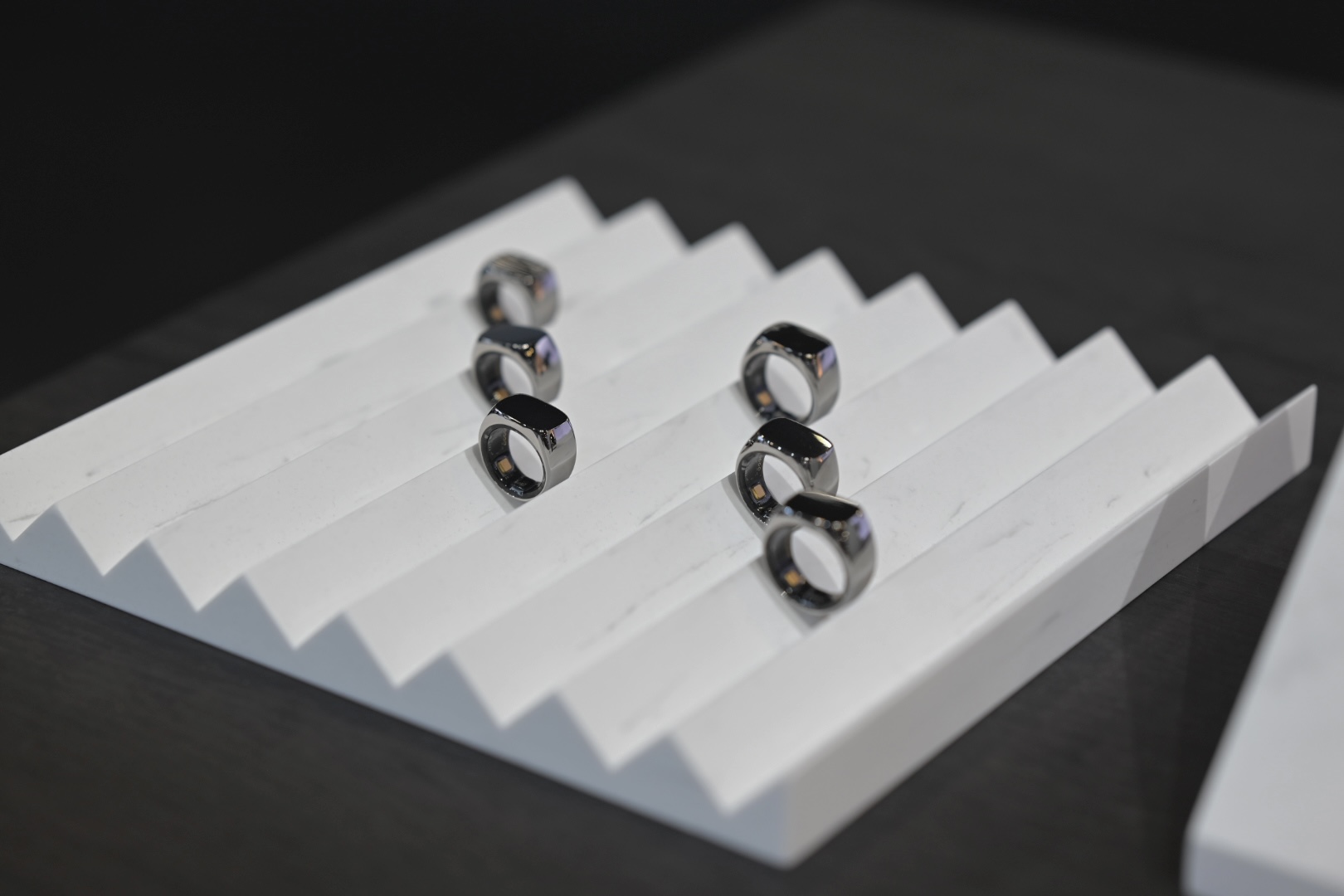 Primer plano de un anillo inteligente plateado Mentoring 2 en la mano de una persona trabajando, con una interfaz digital de batería emocional al fondo.