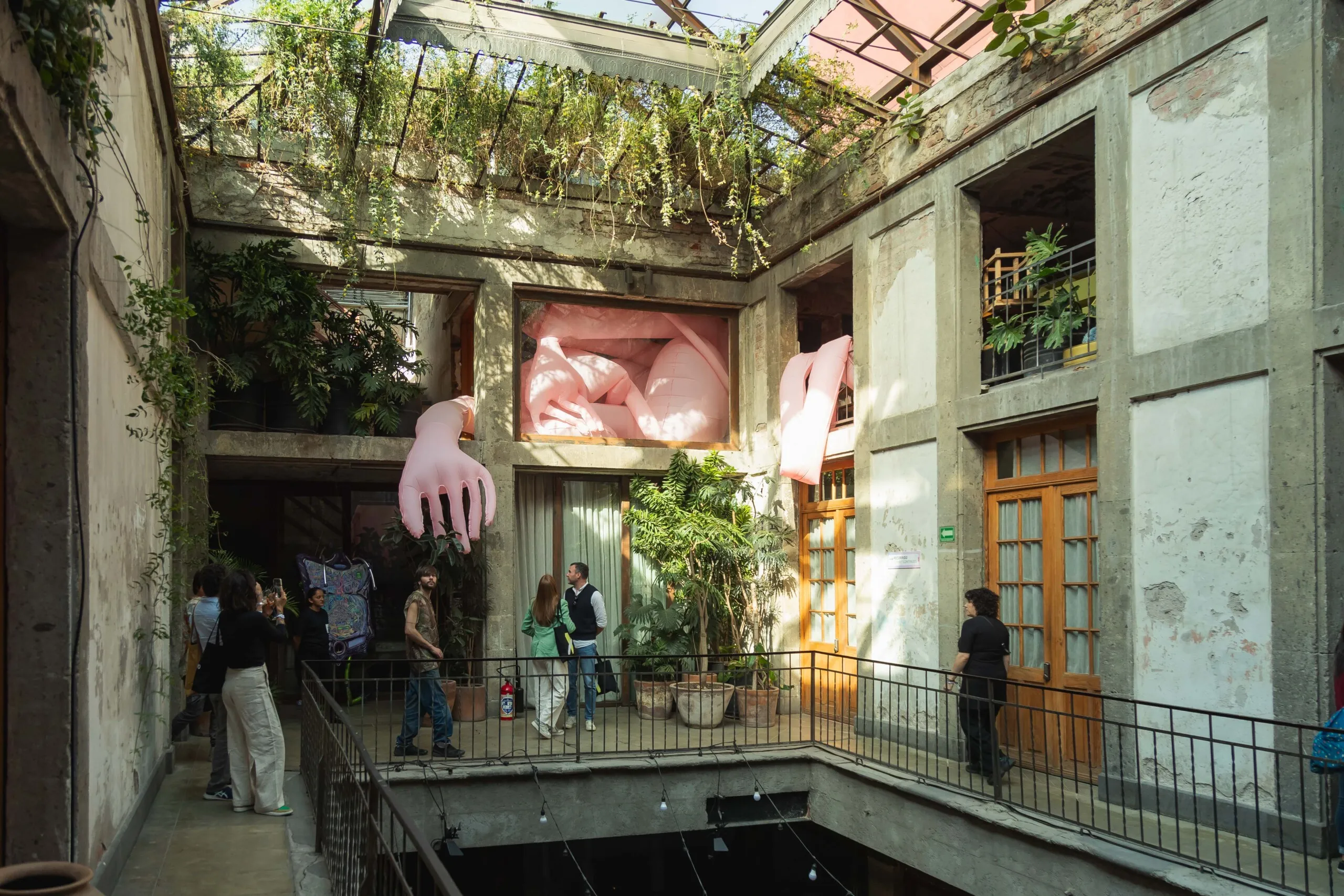 Exposición de arte contemporáneo en Salón ACME dentro de una casona antigua de la Colonia Juárez, con gente admirando obras modernas bajo luces cálidas y neones.