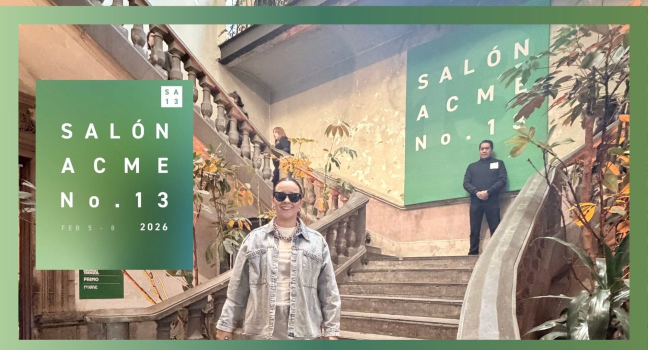 Fotografía de una persona recorriendo una casona histórica con techos altos y paredes desgastadas, donde cuelgan instalaciones de arte moderno y pinturas contemporáneas, iluminada por luz natural.