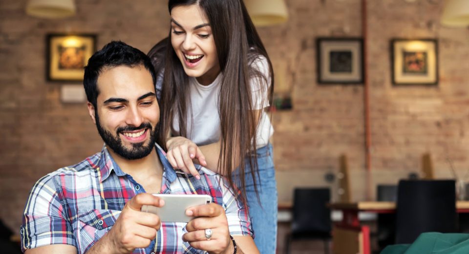 Smartphone emitiendo un holograma de un globo terráqueo con rutas de vuelo en luces neón, representando a la IA SOFIA de Despegar planificando viajes.