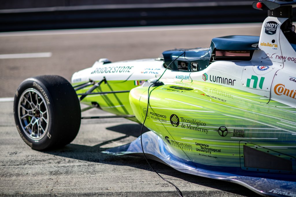 Vehículo autónomo Dallara AV-24 del equipo PoliMOVE-TEC corriendo a alta velocidad en el circuito de Laguna Seca durante el Indy Autonomous Challenge.