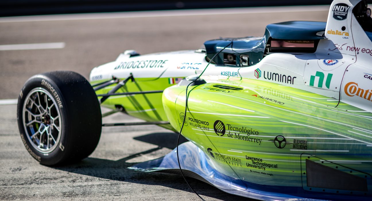 Vehículo autónomo Dallara AV-24 del equipo PoliMOVE-TEC corriendo a alta velocidad en el circuito de Laguna Seca durante el Indy Autonomous Challenge.