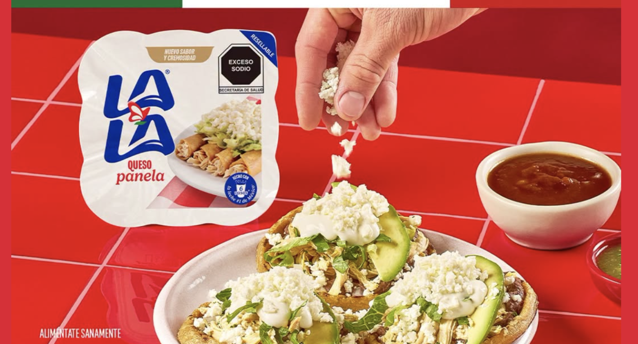 Fotografía de una mesa tradicional mexicana con sopes y enchiladas donde unas manos están agregando generosamente crema y queso extra a los platillos