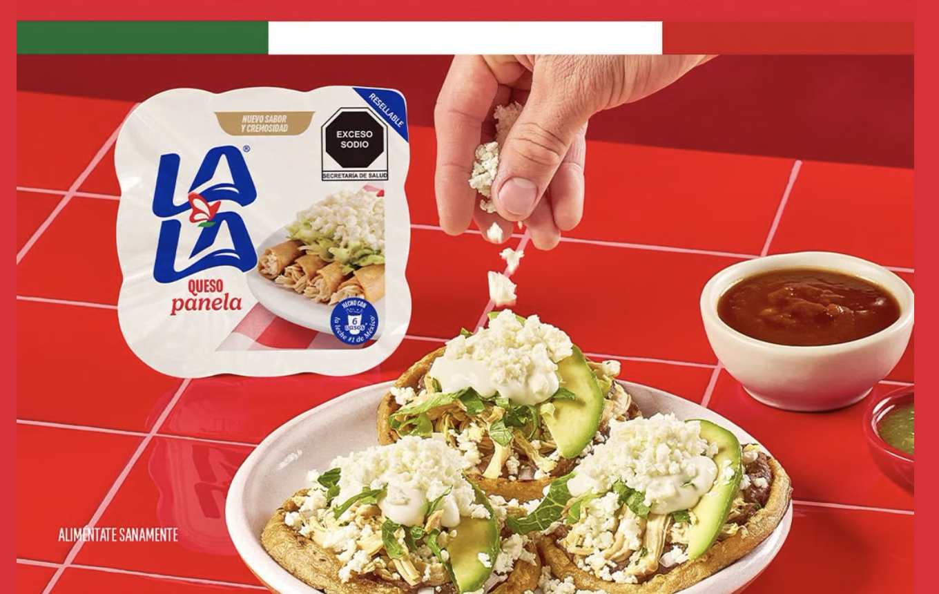 Fotografía de una mesa tradicional mexicana con sopes y enchiladas donde unas manos están agregando generosamente crema y queso extra a los platillos